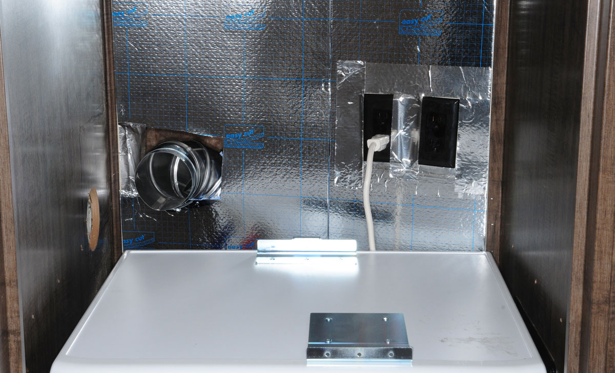 Aluminum-clad foam insulation panels, cut to size and mounted on the front wall inside the washer/dryer closet, cleaned up the holes cut for the dryer vent