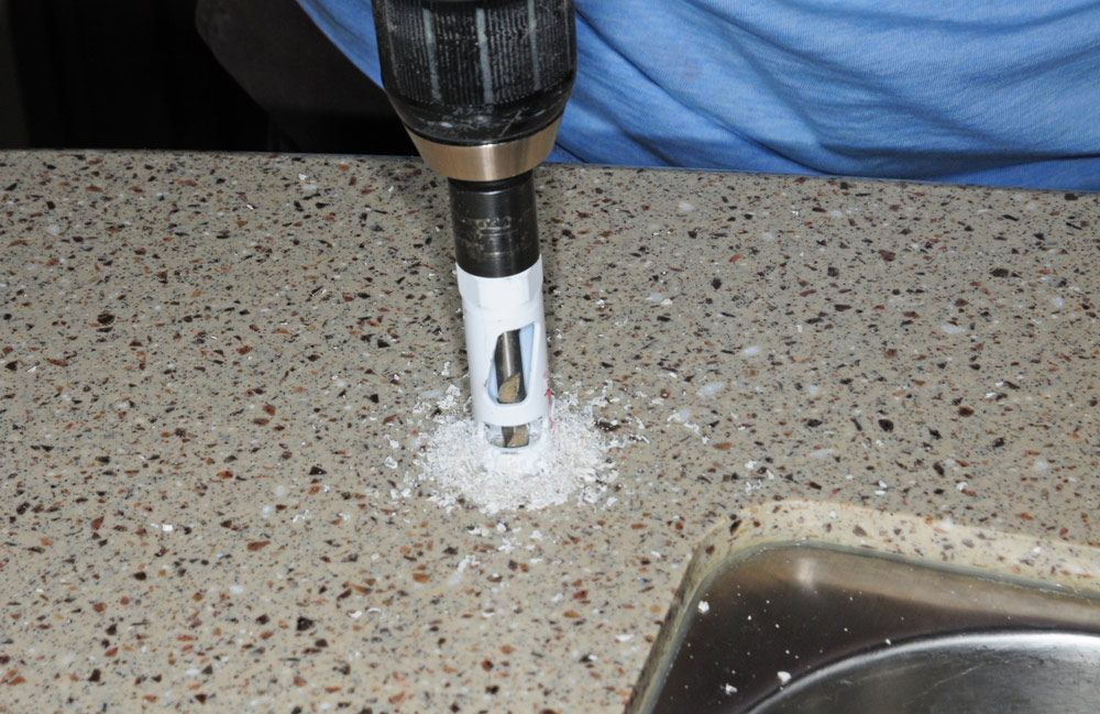 Person drilling a ¾-inch hole into the counter top