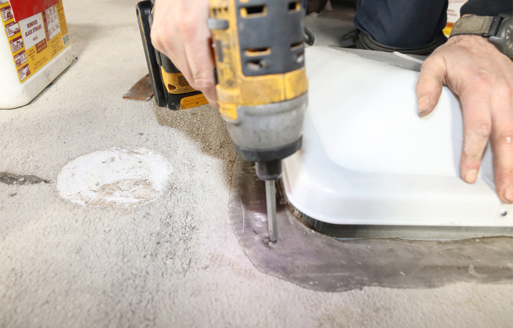 mechanic drills hole into roof vent