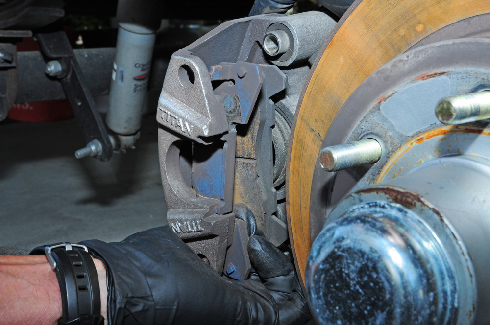 mechanic unbolts and pulls brake caliber