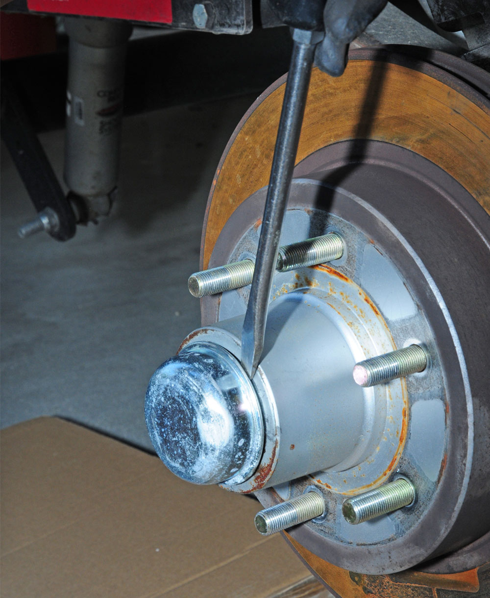 mechanic removes dust cap with screwdriver