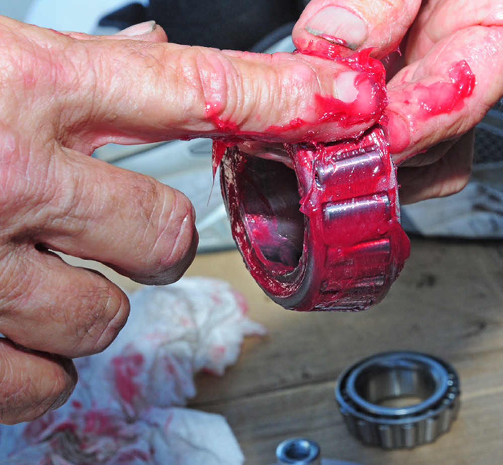 mechanic applies grease by hand to roller bearings