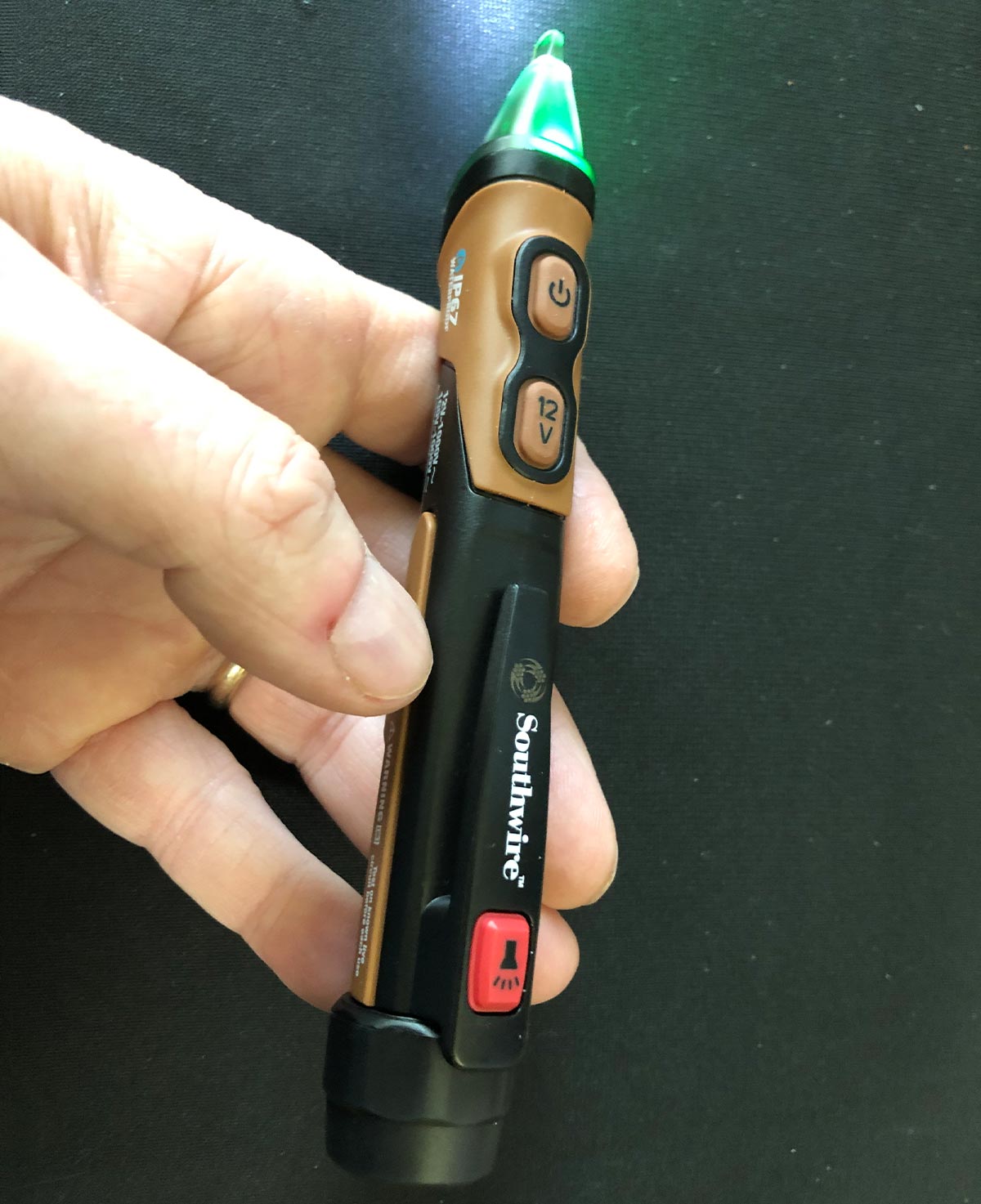 A voltage tester illuminating green