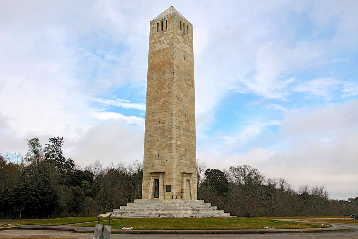 Chalmette Battlefield monument standing tall above the treeline amidst the gravestones