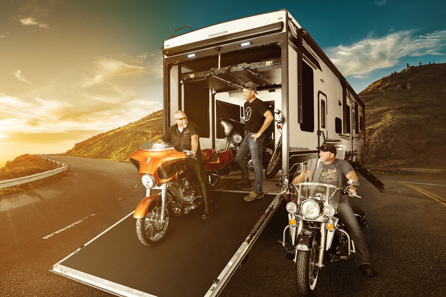 Full-size fifth wheel toy hauler with people on motorcycles