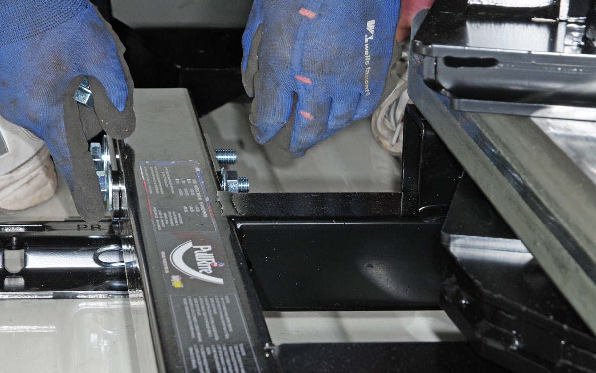 The hitch is placed into the base rail assemblies and bolts are hand tightened