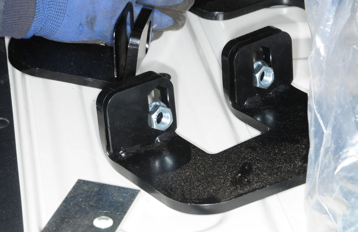 A 1/8-inch tab is located below each slotted bolt hole in the front brackets and is pryed open to allow the flange nuts to be inserted before pushing the tab back into position
