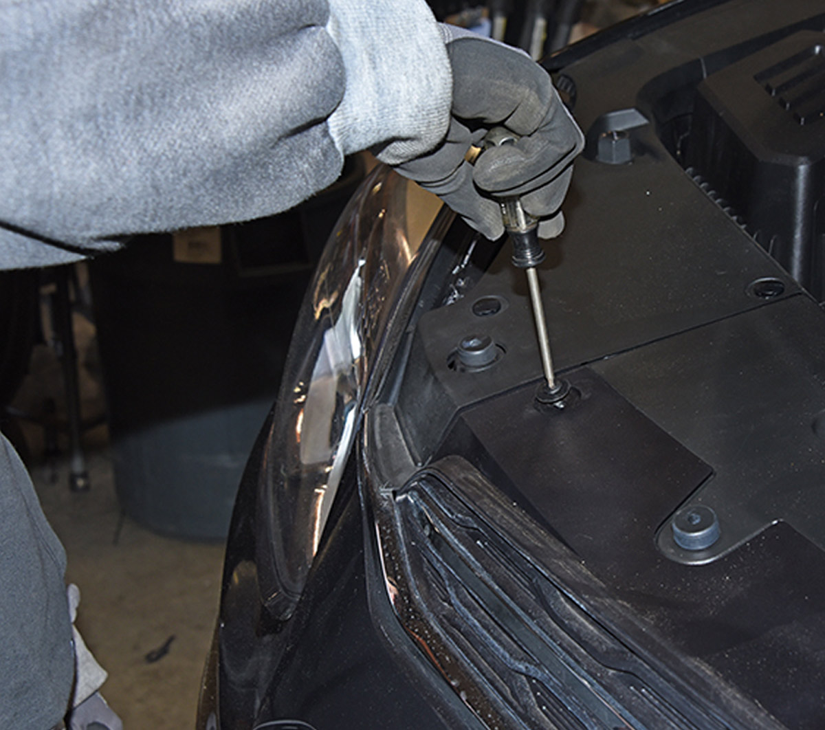 mechanic removes vehicle front fascia to fit baseplate