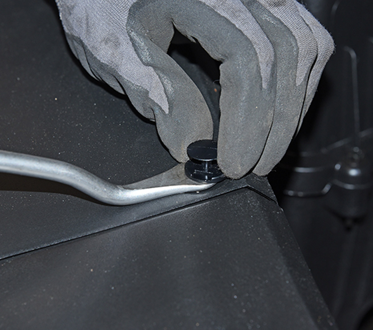 mechanic uses special tool to remove plastic fasteners