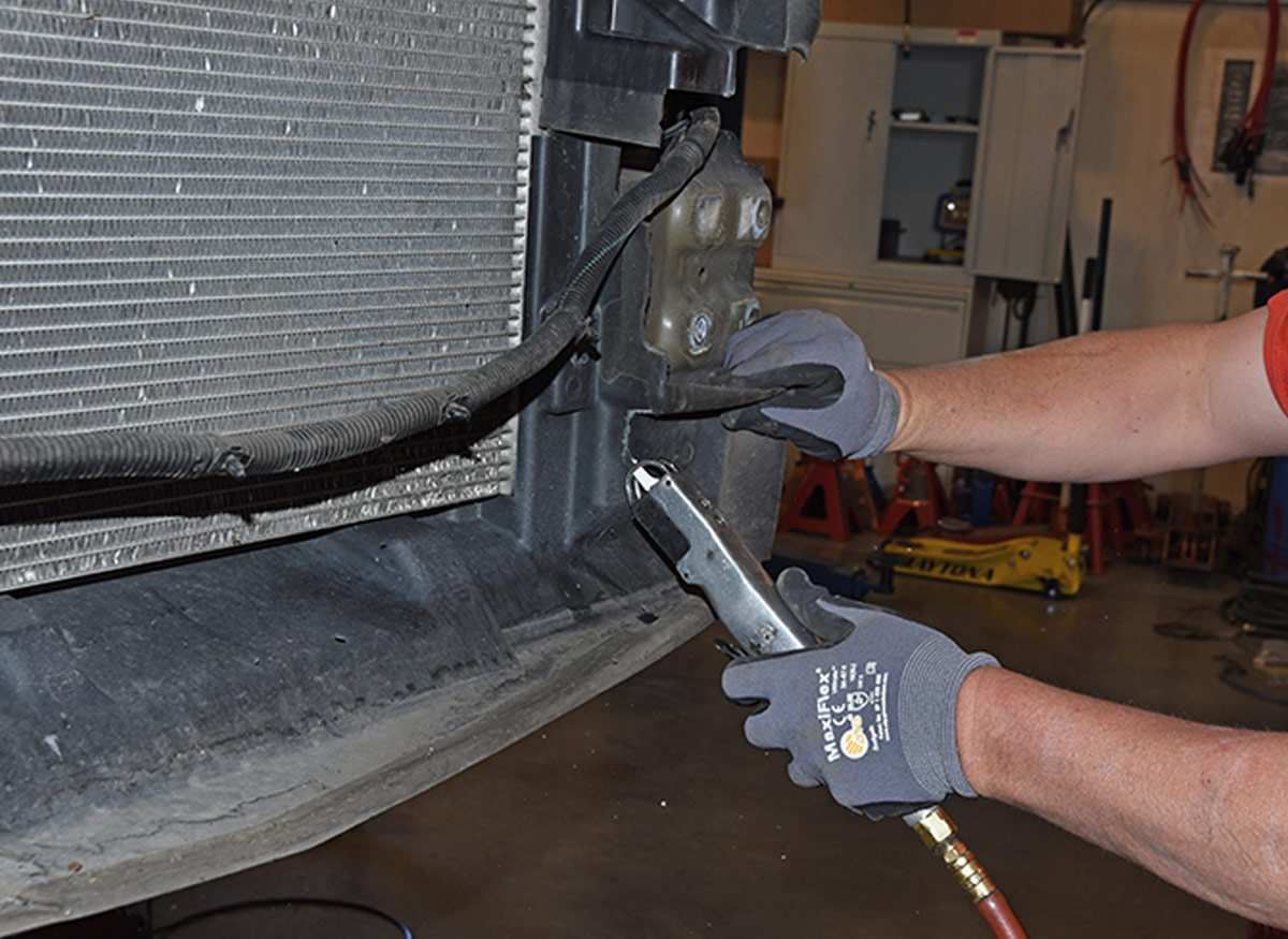 mechanic cuts end of the plastic inner air dam with an air saw