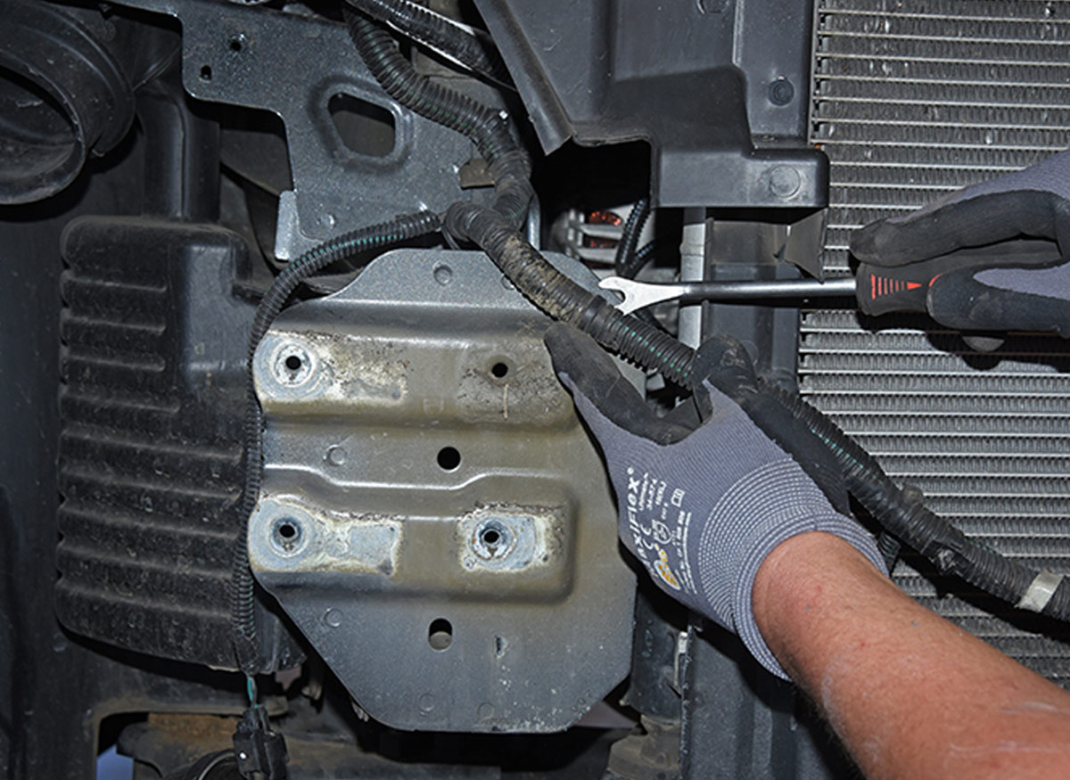 using a plastic fastener remover, mechanic frees harness without damage