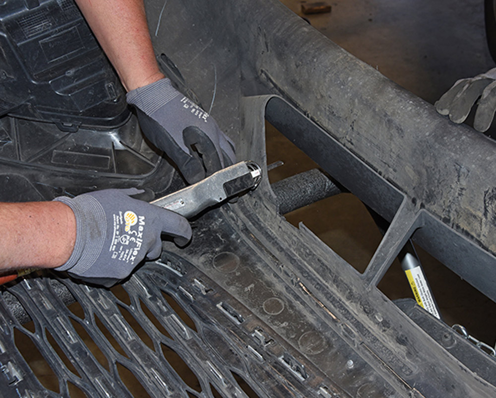 mechanic trims lower fascia to allow baseplate structure arms