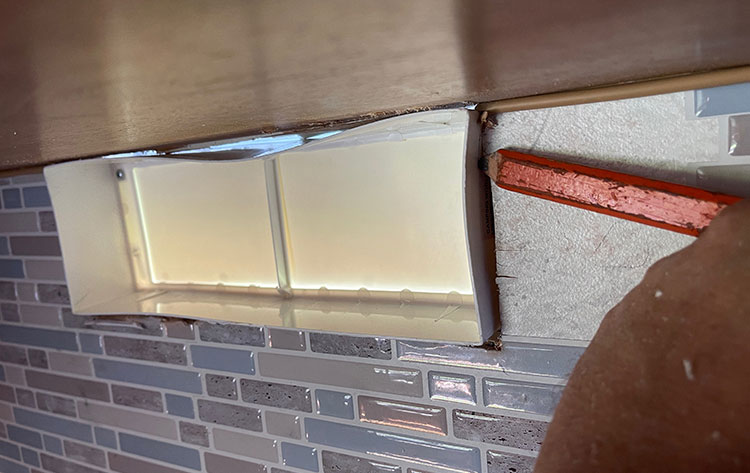 The new vent was thicker than the wall, so we trimmed it to fit