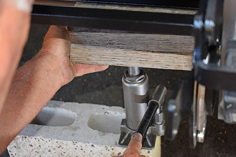 a bottle jack, wood block and brick 