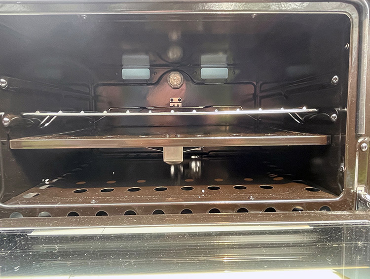 If you opt to use a pizza stone, it must not cover any of the vent holes on the burner shelf, as seen here