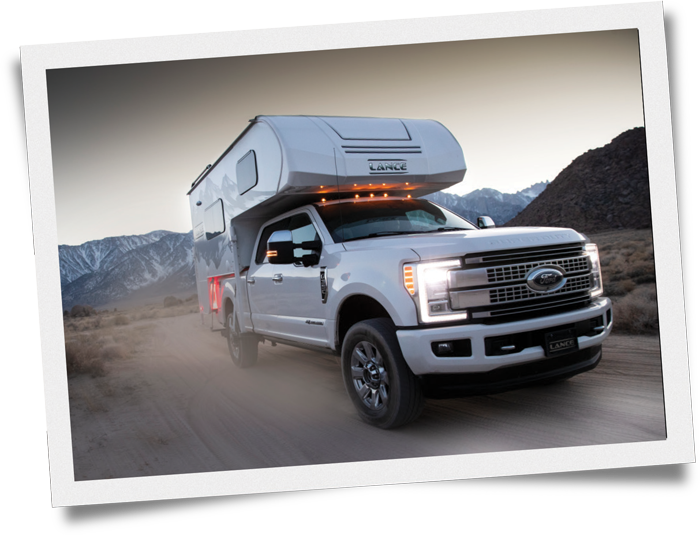 Ford truck driving in the desert with a Lance Camper