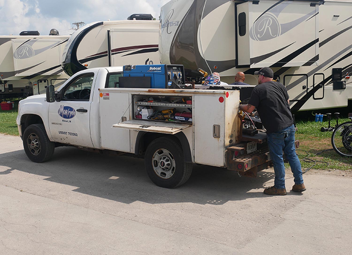 a repair truck is parked in front of a line of RV