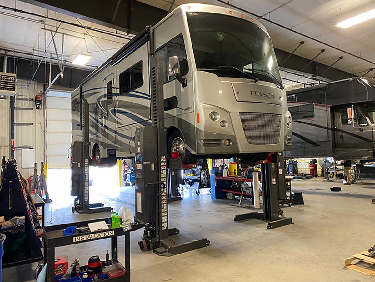 The Itasca motorhome is placed on a four-corner, electric lift and supported by tall jack stands to release the suspension