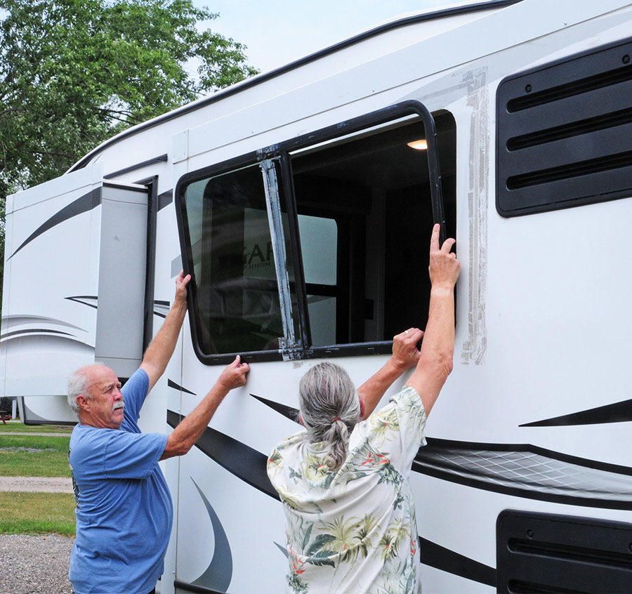 two people installing a window for an RV