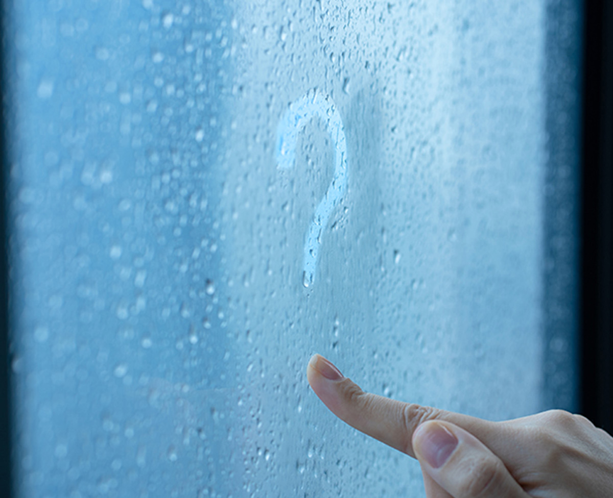 a right hand drawing a question in the condensation of a window