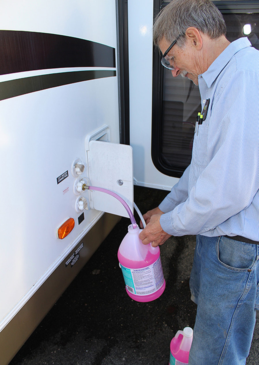 man hosing a pink liquid into his trailer