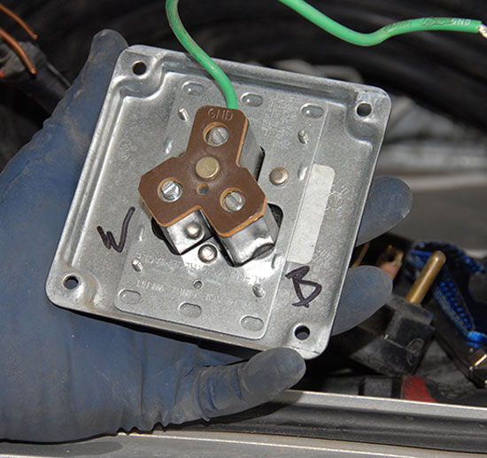 A useful tip is to mark the inside of the cover so you know where the wires go upon re-assembly: “W” for white, “B” for black; the green ground wire remains attached