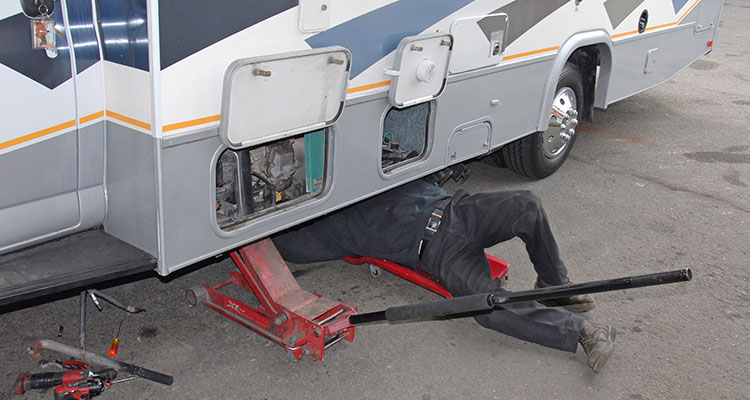 A common floor jack and a square piece of plywood is used to support the generator prior to removal of the mounting brackets