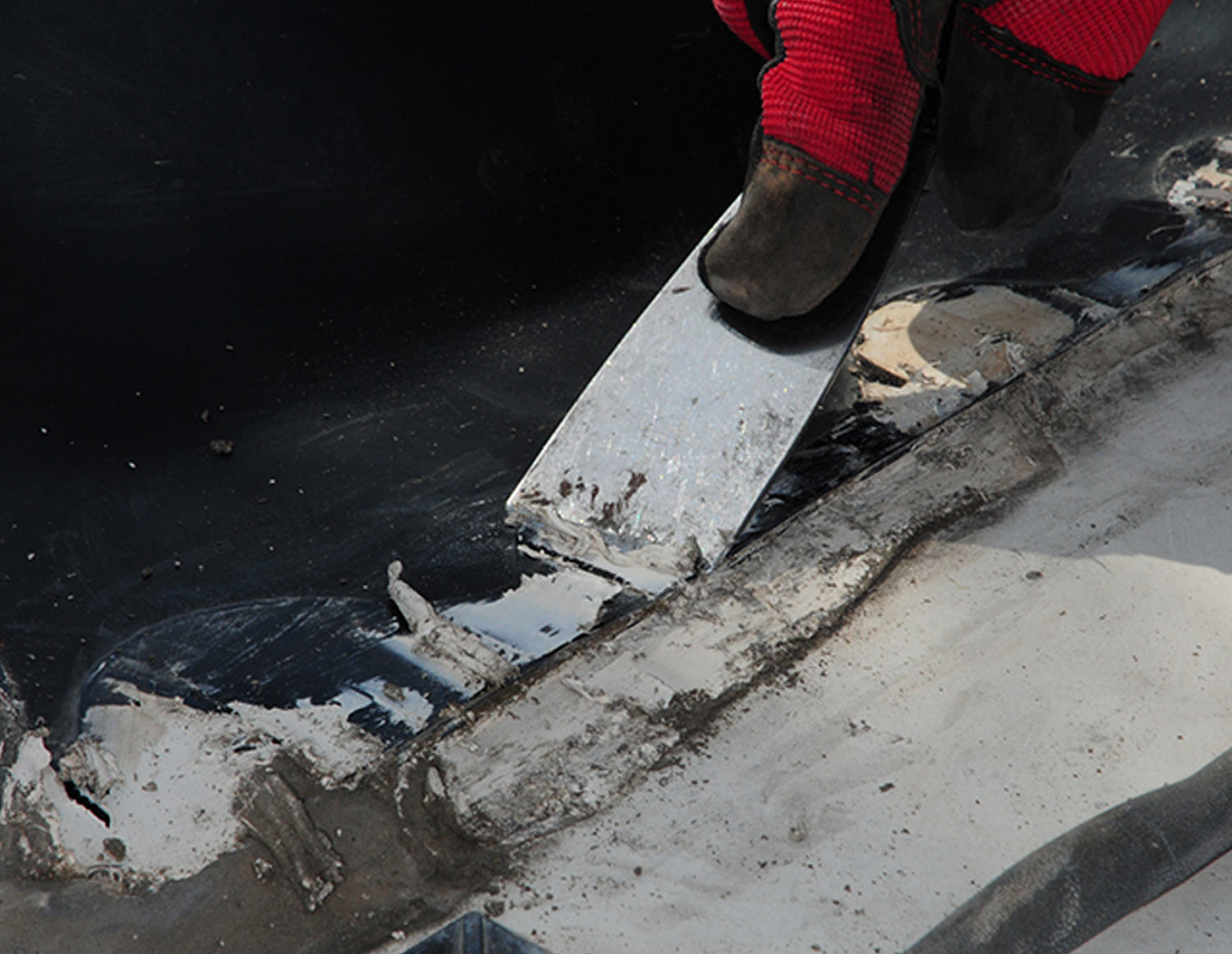 a smaller putty knife is used to remove the old sealant around the screws