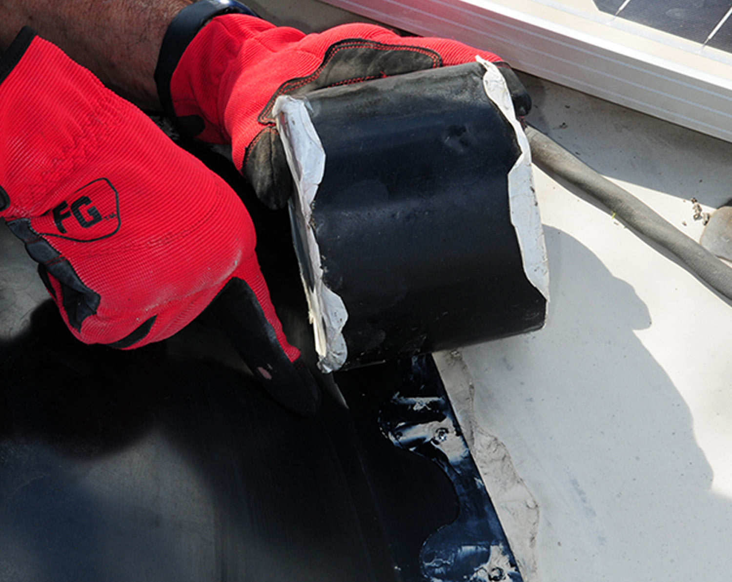 mechanic holds a four in wide roll of black Eternabond tape