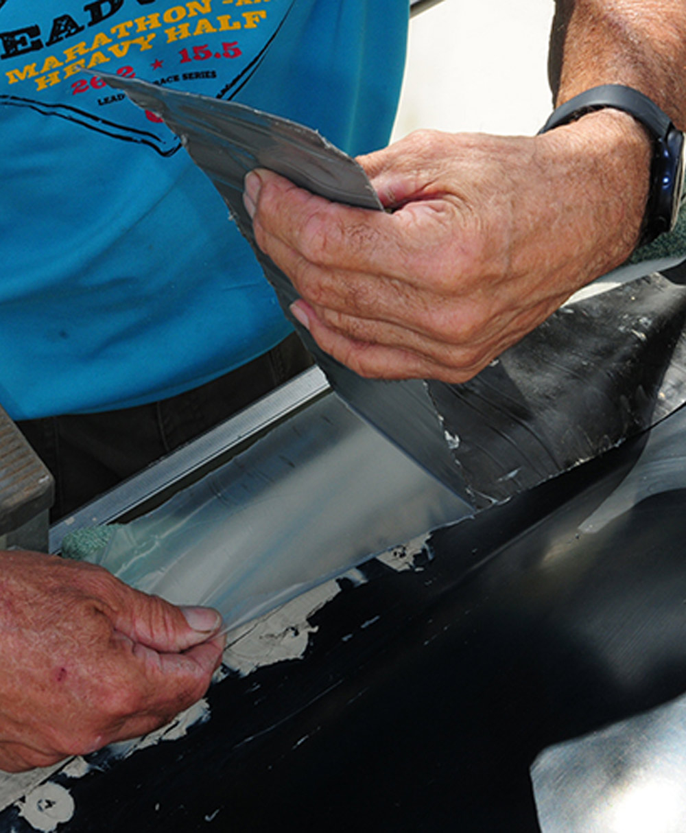 mechanic removes the protective layer just enough to place the tape