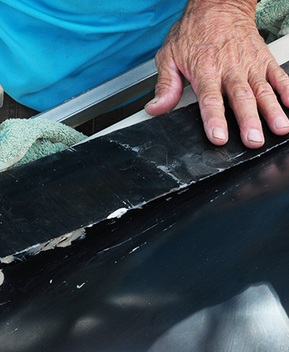 mechanic carefully places the less than forgiving and highly adhesive tape along the skylight