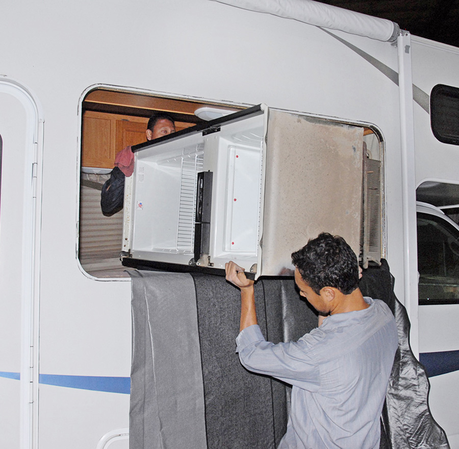 person installing an air conditioning unit in their RV