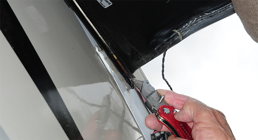 razor knife being used to carefully cut away the glob of silicone sealer