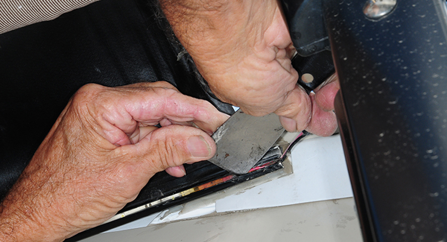 a metal putty knife being used to remove the excess silicone sealant