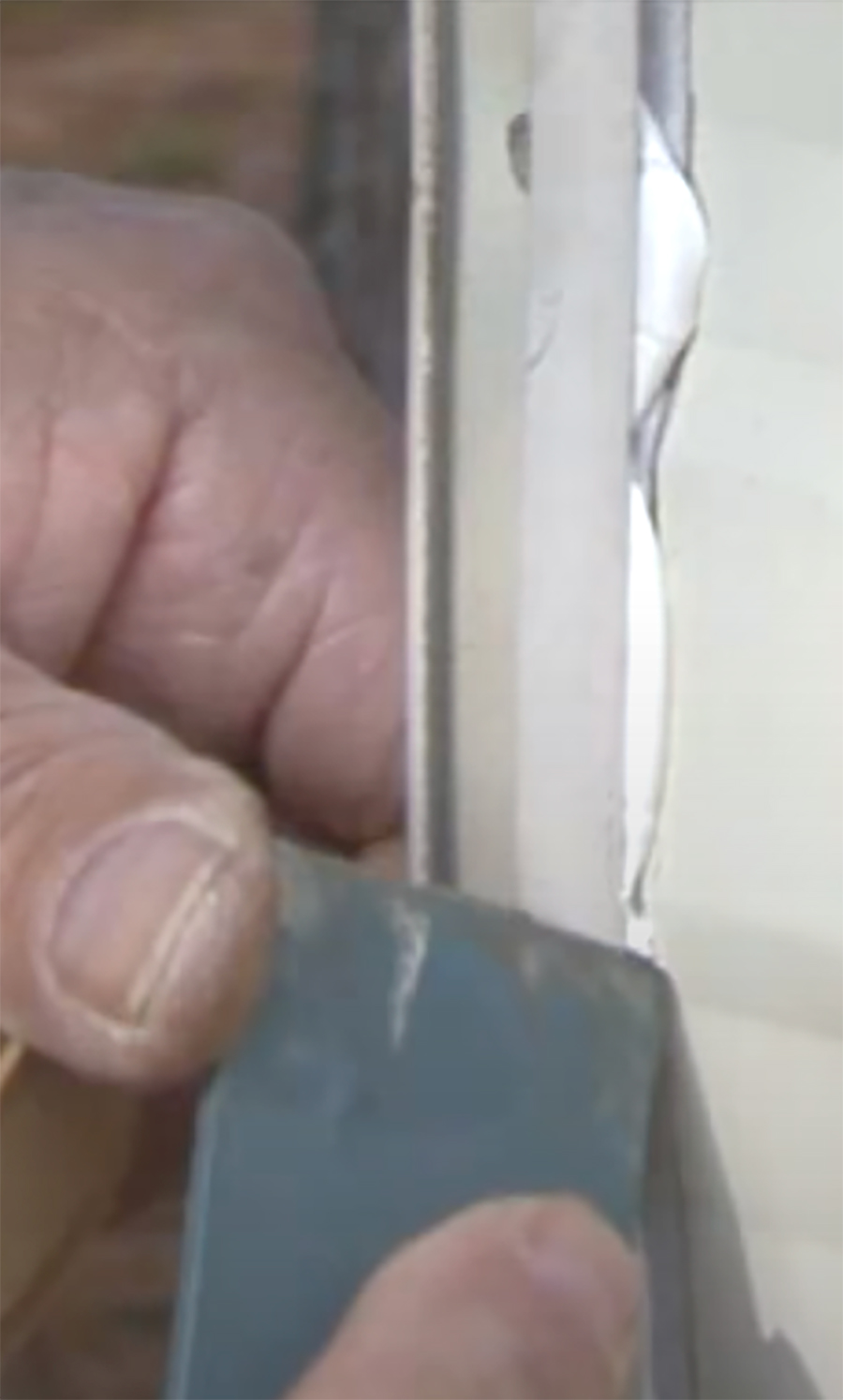 putty knife being used to clean the excess sealant from the edges of the molding