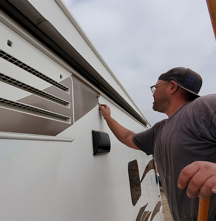 man applying decals to the outside of his RV