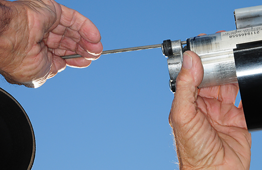 A round file being used to remove sharp burs from the ends of the roller tube channel