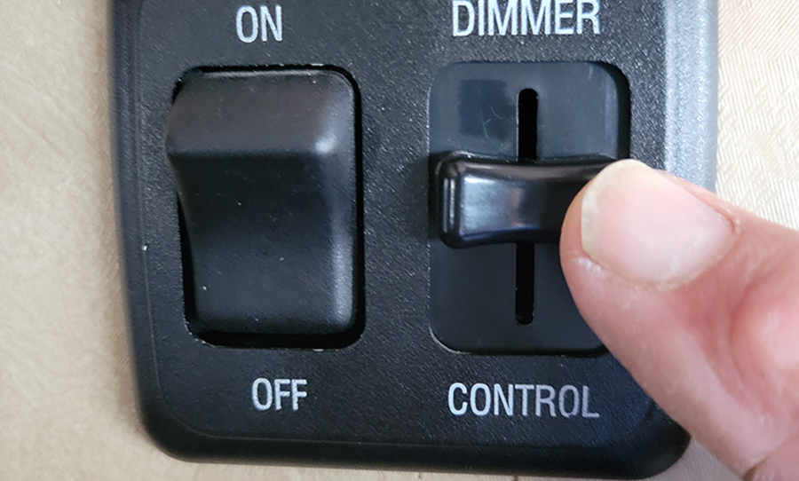 hand controlling the dimmer on a light switch