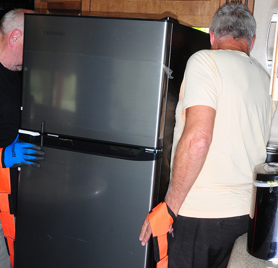 two people installing a fridge