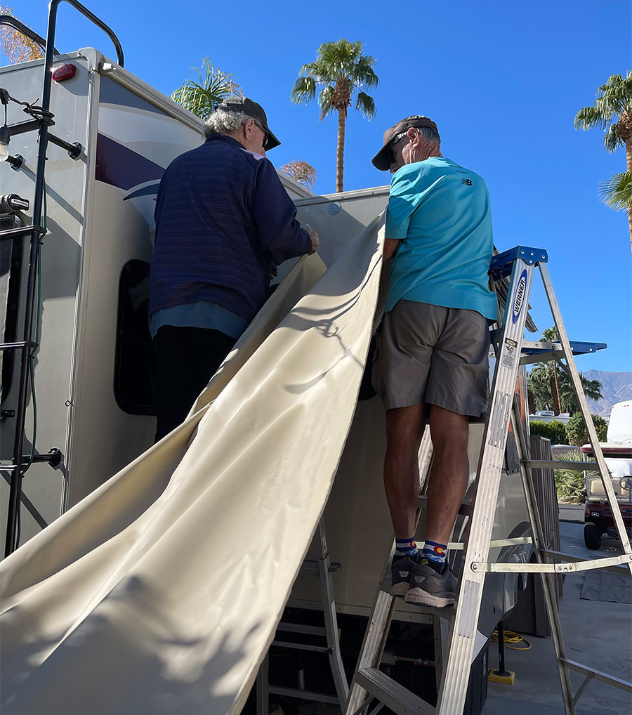 two people working on the outside of an RV