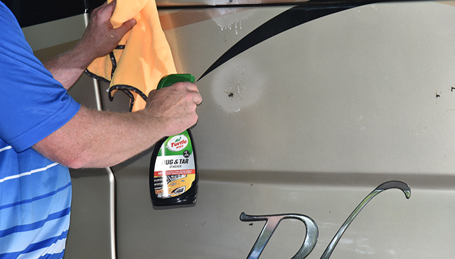 man applying a cleaning spray to an RV