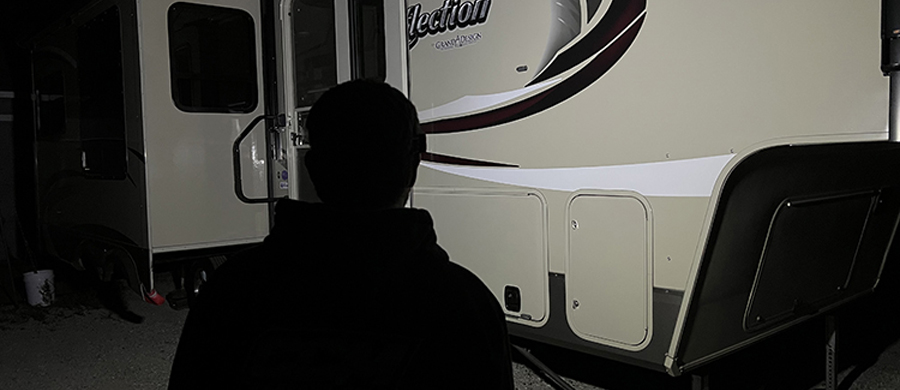 silhouette of person in front of their trailer at night with a light on