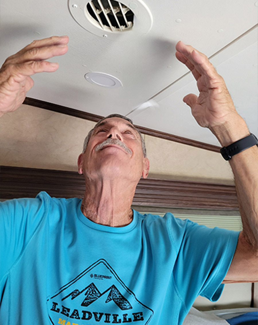 man standing under AC vent in his RV