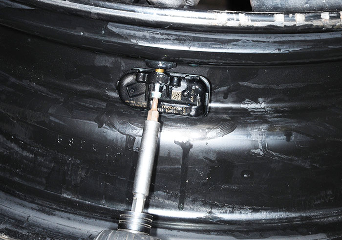 The factory sensor is unscrewed from the valve stem before it can be removed from the wheel