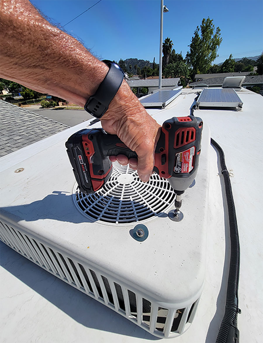 This air-conditioner model has four bolts on top that must be removed to lift off the shroud