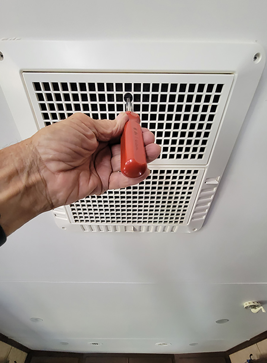 A screwdriver is used to unlock the return-air access panel with the filter attached