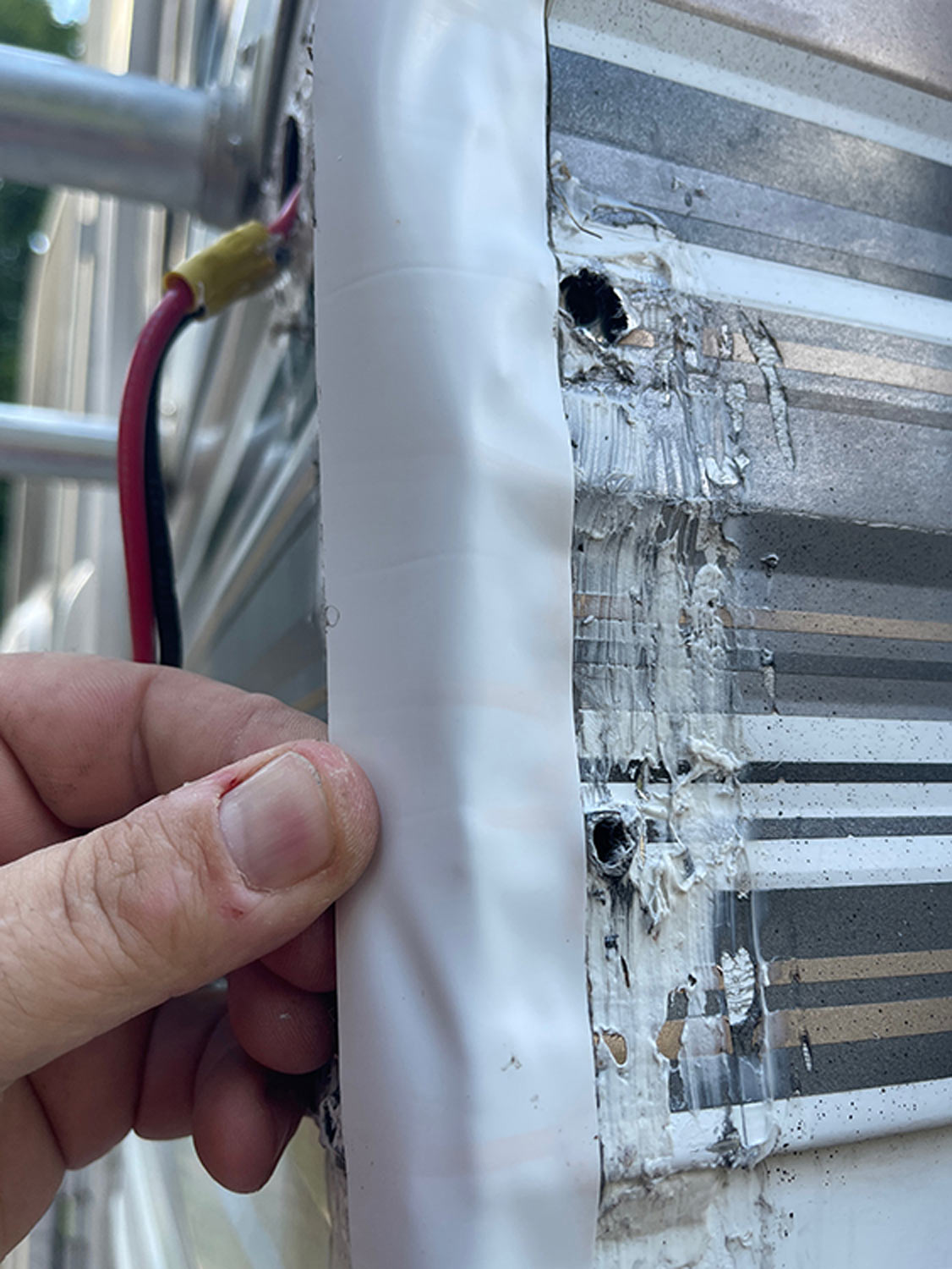 close up of mechanic applying a long strip of Eternabond tape to the vertical corner