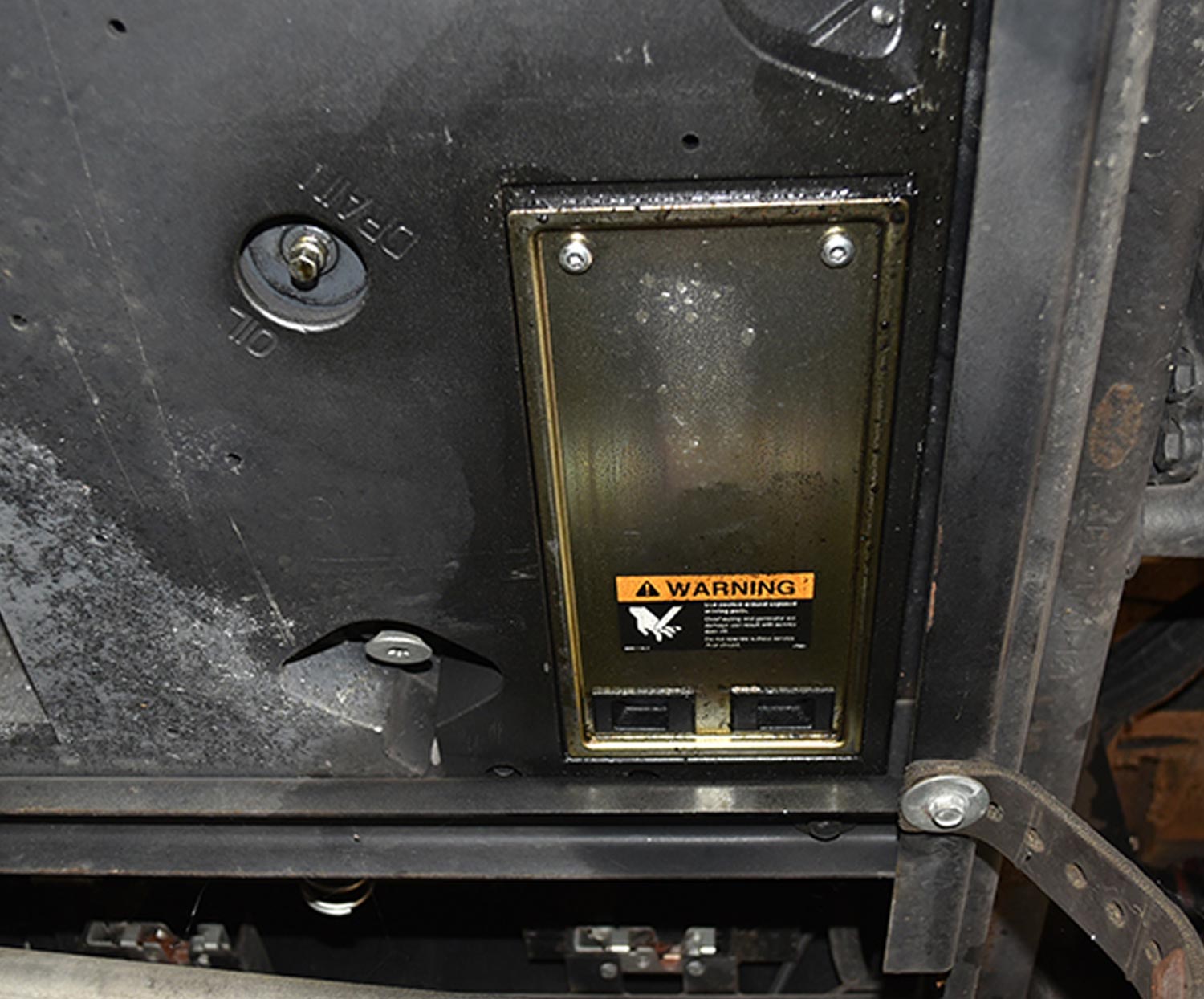 view of the gold-colored access panel near the oil drain opening