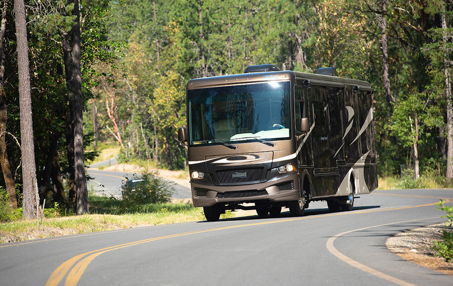 RV driving on a road through the woods