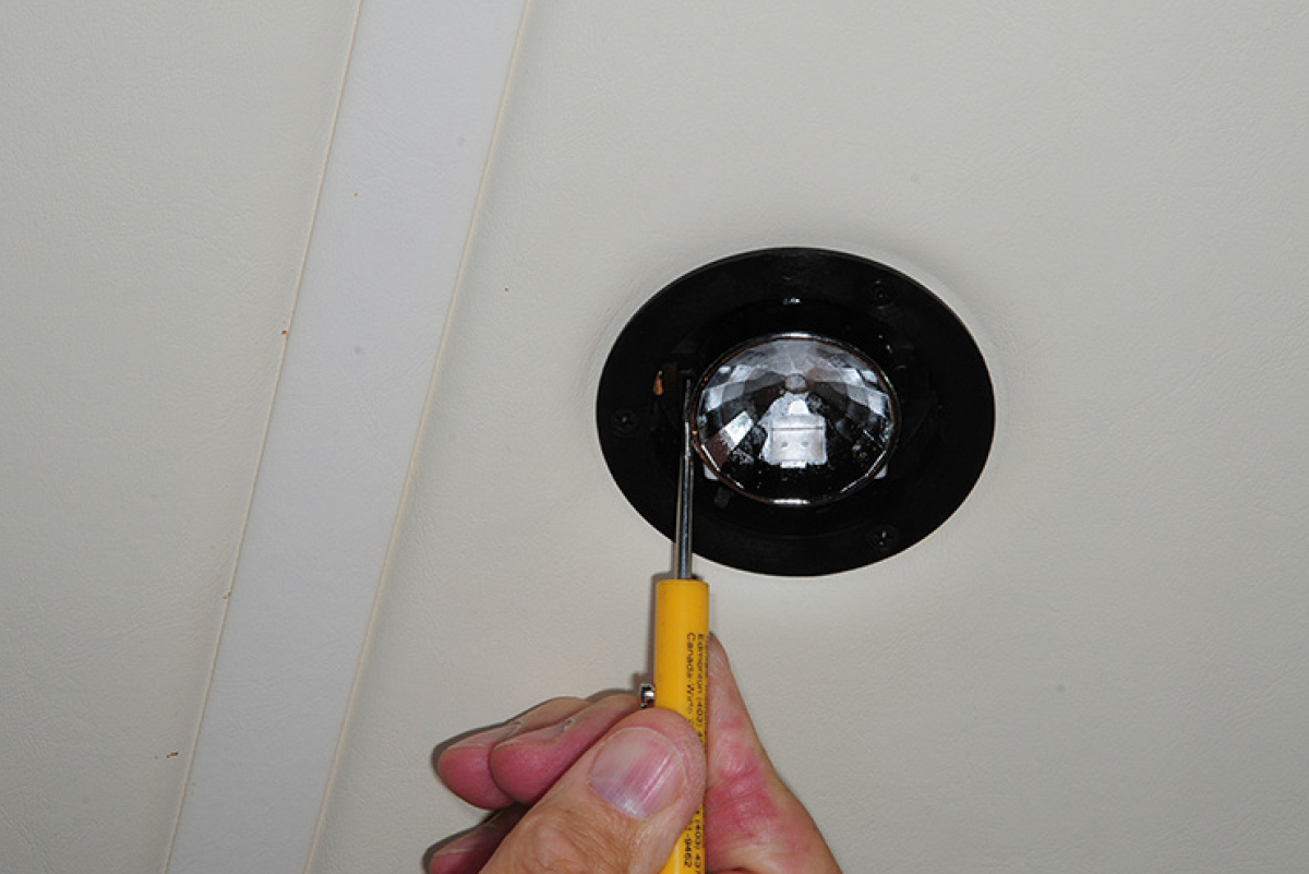 A small screwdriver is used to pry the reflector from the fixture housing